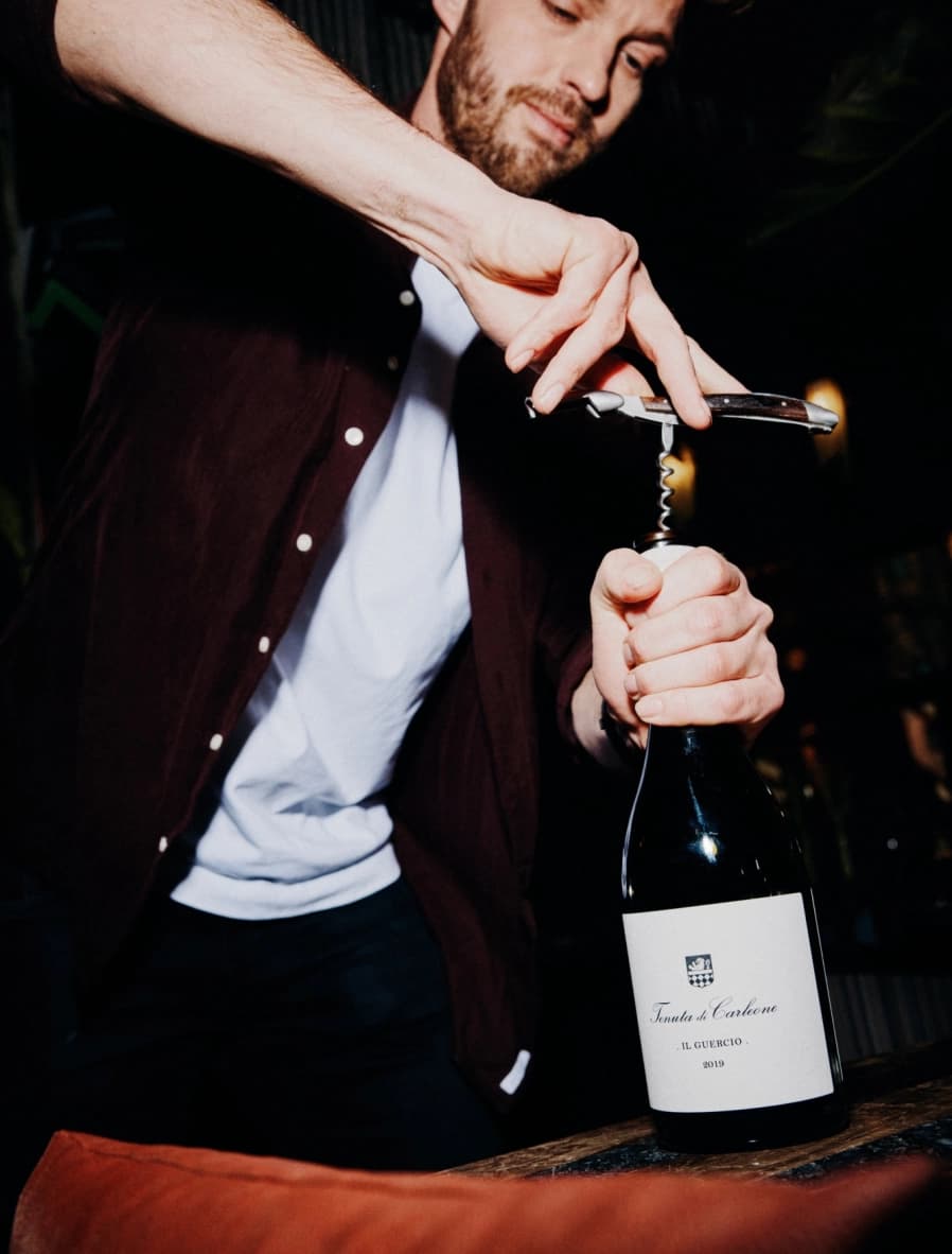 Jurjen opent een zorgvuldig gekozen fles wijn